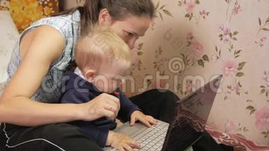 年轻<strong>女子</strong>带着儿子<strong>坐在</strong>家里的<strong>沙发上</strong>，拿着笔记本电脑。 仔细看屏幕，按下键。
